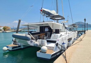 A yacht docked at a marina with a covered deck area, a lounge chair, and a small table. - Sun-Kissed Sailing Adventure in the Ionian Islands, Lefkada (Lefkada)