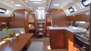L’intérieur d’un yacht comprenant un coin repas, une petite cuisine et un petit espace salon.