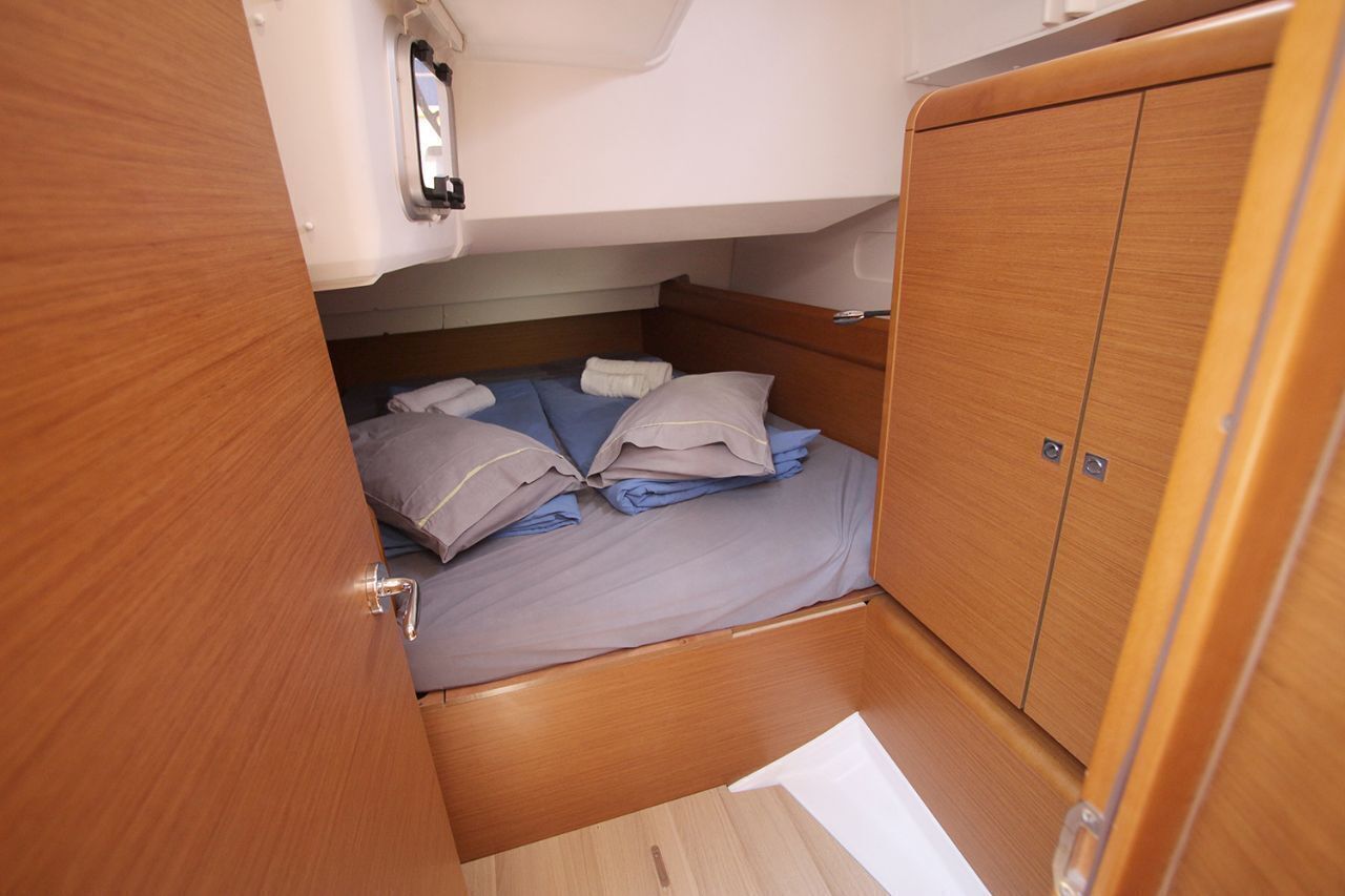 Une petite cabine comprenant un lit, une armoire et une petite fenêtre.