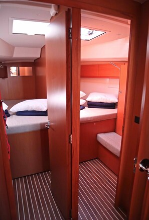 A compact cabin with a bunk bed, a small seating area, and a skylight. - Sun-Kissed Sailing Adventure in Islas Sarónicas (Alimos)