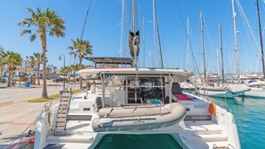 Un port esportiu amb vaixells amarrats, un flotador i una escala a un vaixell.