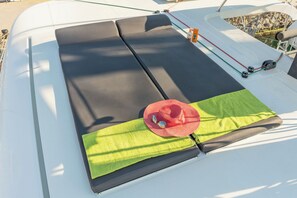 A boat's deck with a green mat, a red hat, and a black cushion. - Sun-Kissed Sailing Adventure in Islas Sarónicas (Alimos)