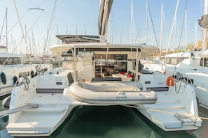 A marina with several boats docked, featuring a cabin with a dining area and a covered deck. - Sun-Kissed Sailing Adventure in Islas Sarónicas (Alimos)