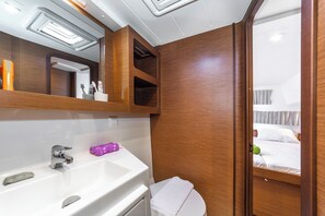A bathroom with a white sink, mirror, and wooden cabinets. - Sun-Kissed Sailing Adventure in Islas Sarónicas (Alimos)