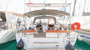 Een zeilboot in de haven, met een overdekt dek, zitplaatsen en een reddingsboei.