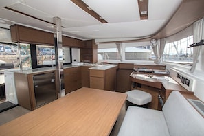 A compact galley with a wooden table, a bench, and a compact kitchenette. - Sun-Kissed Sailing Adventure in the Saronic Islands (Laurium)