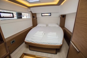 Ein kleines Schlafzimmer mit Bett, zwei Fenstern, einem Fernseher und einem kleinen Stauraumschrank.