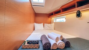 Quarto compacto com cama, uma pequena janela e um claraboia.