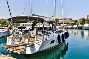 Ein Yachthafen mit einer dort liegenden Segelyacht, mit überdachter Terrasse, Sitzgelegenheit und einem Rettungsring.