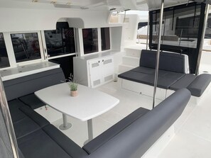 A boat interior with a dining area, seating, and a small table with a plant. - Sun-Kissed Sailing Adventure in Islas Sarónicas (Alimos)