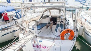 Una barca di nome Lydia ormeggiata in un porto turistico, con altre imbarcazioni, un salvagente e una scaletta.