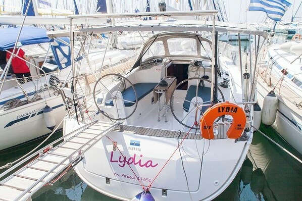 A boat named Lydia docked at a marina with other boats, a lifebuoy, and a ladder.