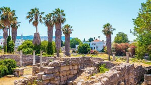 Ancient ruins with stone columns and walls, surrounded by greenery and palm trees. - Sun-Kissed Sailing Adventure in the Dodecanese Islands (Kos)