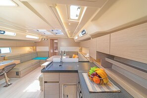 A compact kitchen with a central island, a seating area, and a small dining table. - Sun-Kissed Sailing Adventure in the Saronic Islands (Laurium)
