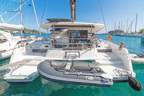 A sailboat docked at a marina with a covered deck area, a small inflatable dinghy, and a lifebuoy. - Sun-Kissed Sailing Adventure in the Ionian Islands, Lefkada (Lefkada)