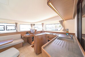 A compact galley with a sink, stove, and seating area. - Sun-Kissed Sailing Adventure in the Ionian Islands, Lefkada (Lefkada)