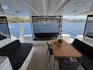 Ein Bootsdeck mit Tisch, Sitzgelegenheiten und Blick auf das Wasser.
