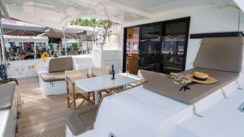 Une terrasse ensoleillée avec une table, des chaises et un coin salon confortable avec des coussins.