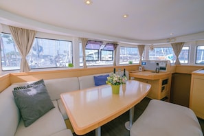 L’intérieur d’un bateau comprend un coin repas, des sièges rembourrés, une petite table agrémentée d’un vase de fleurs et un panneau de commande.