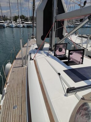 A sailboat deck with a wooden floor, white deck, and a view of other boats in the marina. - Sun-Kissed Sailing Adventure in Islas Sarónicas (Alimos)
