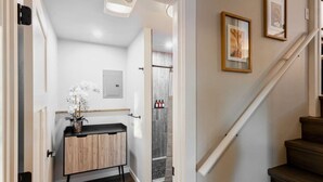 A hallway with a wooden cabinet, a door leading to a bathroom, and a staircase.