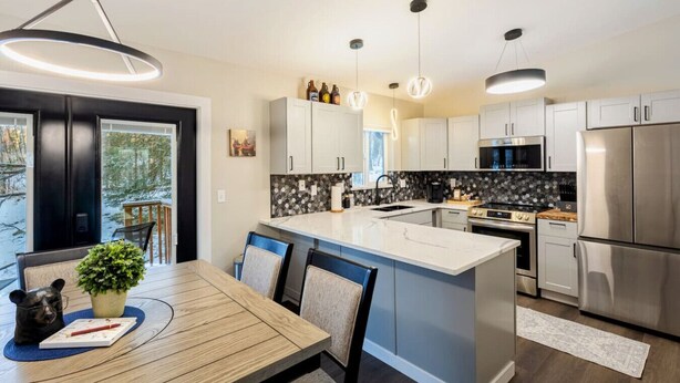 A modern kitchen with a central island, stainless steel appliances, and pendant lighting.