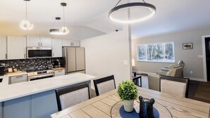 A modern kitchen with white cabinets, stainless steel appliances, and pendant lighting.