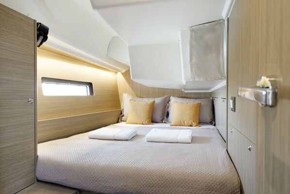 Ein kleines, helles Schlafzimmer mit einem Bett, Kissen und einem kleinen Fenster.