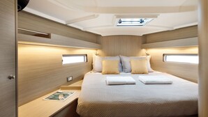 Ein gemütliches, helles Kabinenzimmer mit Bett, Nachttischen und einem kleinen Fenster.