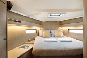 A compact, well-lit cabin with a bed, bedside tables, and a small window. - Sun-Kissed Sailing Adventure in Islas Sarónicas (Alimos)
