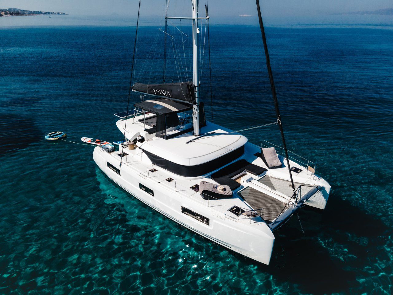 Uno yacht bianco con una copertura sul ponte, acqua cristallina e una costa in lontananza.