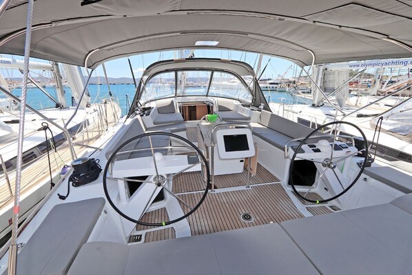 A boat deck with a steering wheel, a small table, and a seating area. - Sun-Kissed Sailing Adventure in the Saronic Islands (Laurium)