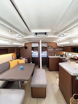 A compact, well-lit interior with a dining area, a kitchenette, and a small sleeping area. - Sun-Kissed Sailing Adventure in Islas Sarónicas (Alimos)