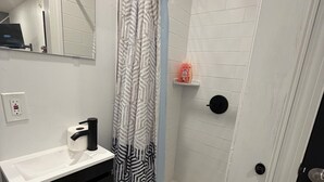 A modern bathroom with a shower, a sink with a mirror, and a toilet.
