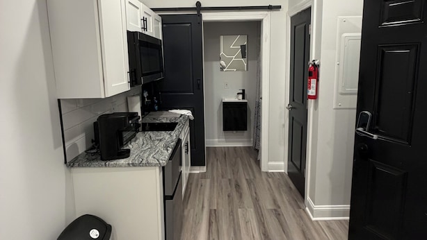 A modern kitchen with white cabinets, a black countertop, and a microwave.