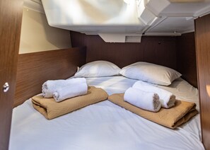 Ein kleines Hotelzimmer mit einem Einzelbett, zwei Kissen und zwei ordentlich gefalteten Handtüchern.