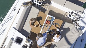 Een dek met een boot, een tafel, stoelen en een stuurwiel.