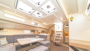 A compact RV interior with a kitchenette, a dining area, and a seating area with a table and cushions. - Sun-Kissed Sailing Adventure in the Dodecanese Islands (Kos)