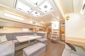 Ein kompaktes Wohnmobil-Interieur mit Küchenzeile, Essbereich und Sitzgruppe mit Tisch und Kissen.