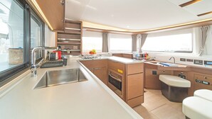 Een kleine keuken met een spoelbak, fornuis, oven en een zithoek.