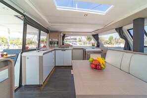 A yacht interior with a dining area, kitchenette, and a view of the marina. - Sun-Kissed Sailing Adventure in the Saronic Islands (Laurium)