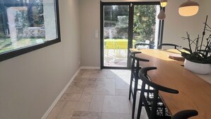 Un comedor moderno con un amplio ventanal, una puerta corrediza de vidrio que da a un balcón, e iluminación colgante.