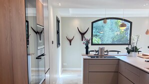 Una cocina moderna con una isla central, armarios de madera y un amplio ventanal con vistas al verdor.