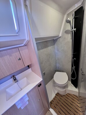 Une petite salle de bain comprenant une douche, des toilettes et un lavabo.
