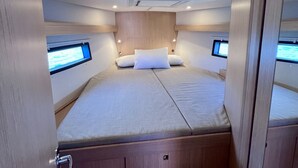 Ein kompakter, gut beleuchteter Raum mit einem Bett, zwei Bildschirmen und einem Holzkopfende.