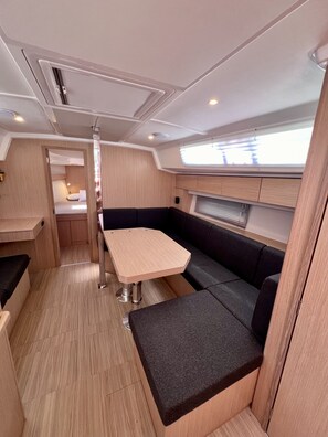A compact interior with a table and seating, a window, and a door leading to another room.