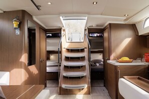 A compact interior with a bunk bed, a small kitchenette, and a skylight. - Sun-Kissed Sailing Adventure in Islas Sarónicas (Alimos)