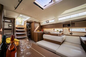A compact, well-lit interior with a kitchenette, seating area, and a window providing a view. - Sun-Kissed Sailing Adventure in Islas Sarónicas (Alimos)