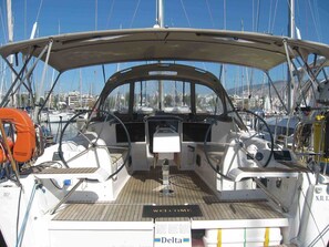 Ein Bootsdeck mit einem 'WELCOME'-Schild, einem Steuerlenkrad und einem Rettungsring.
