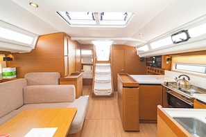 A compact RV interior with a kitchenette, a dining area, and a sleeping berth.